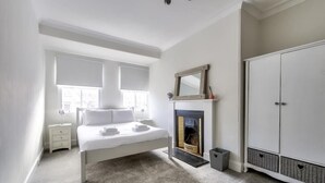 A bedroom with a bed, a fireplace, a wardrobe, and a nightstand. - Modern Royal Mile 2 bed Flat Edinburgh - Pass the Keys (Edinburgh)