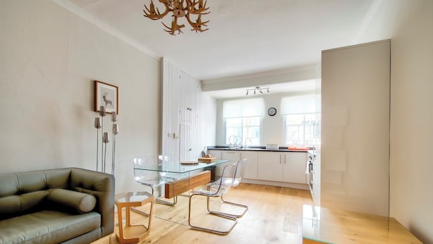 A modern living room with a glass dining table, leather sofa, and wooden flooring. - Modern Royal Mile 2 bed Flat Edinburgh - Pass the Keys (Edinburgh)