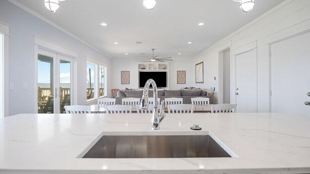 A modern kitchen with a large island, white cabinetry, and pendant lighting.