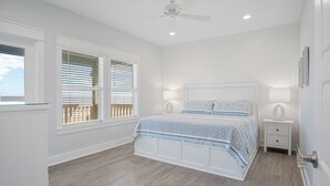 A bedroom with a bed, two bedside tables, a ceiling fan, and a window with blinds.