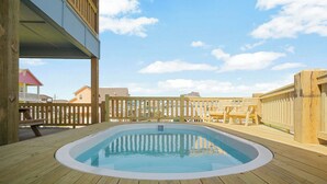 A wooden deck with a swimming pool, wooden fences, and a clear sky.