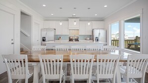 A modern kitchen with white cabinetry, a central island with seating, and pendant lighting.
