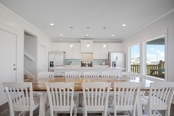 A modern kitchen with white cabinetry, a central island with seating, and pendant lighting.