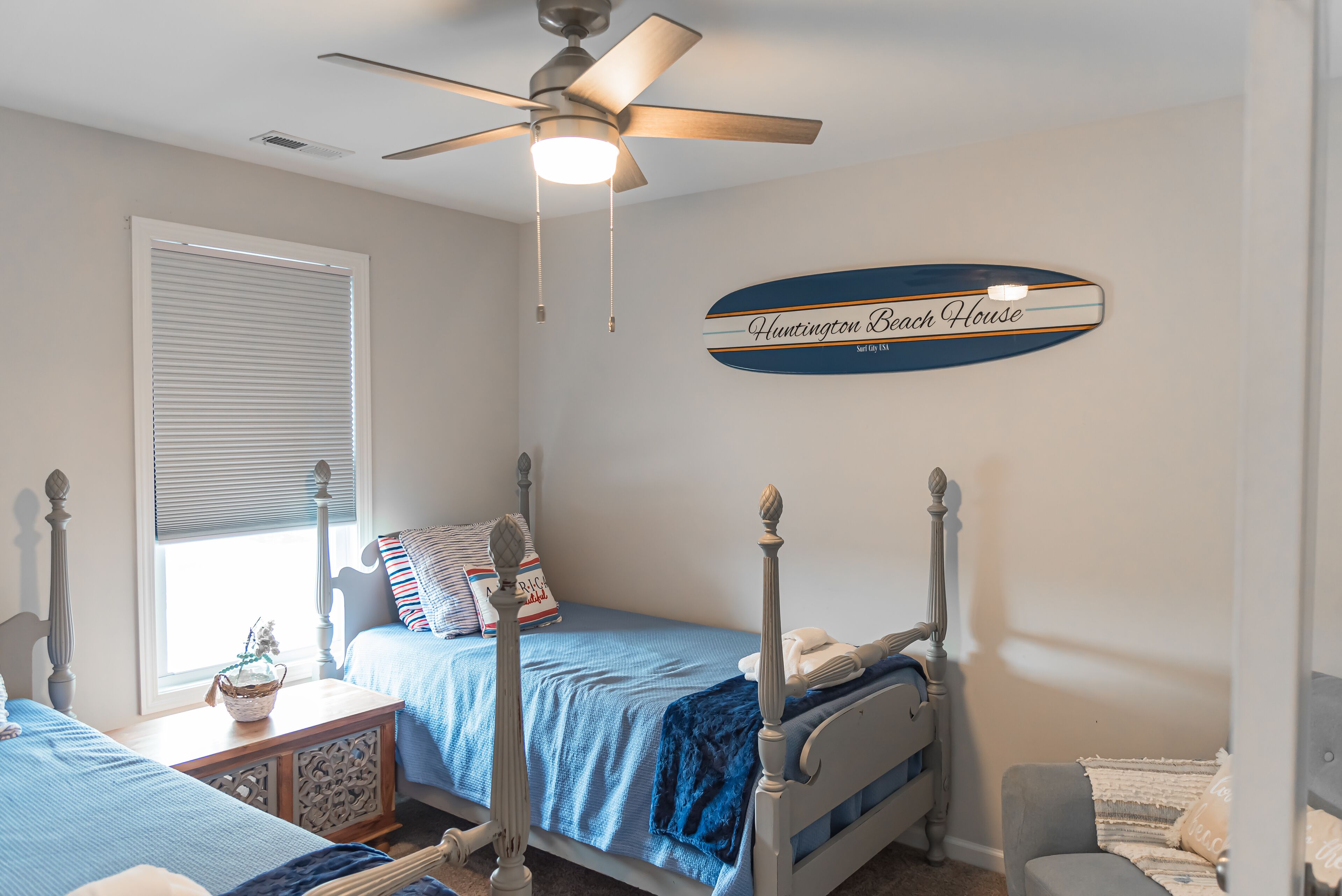 Un dormitorio con cama, mesita de noche, cómoda, ventilador de techo y un letrero en la pared.