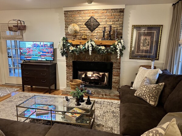Una sala de estar con chimenea, televisor, mesa de centro y sofá.