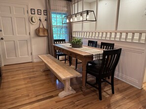 A dining area with a wooden table, black chairs, a bench, and a hanging light fixture.