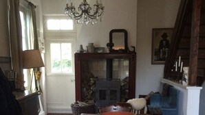 A dining room with a wooden table, chairs, a chandelier, and a vase of flowers.