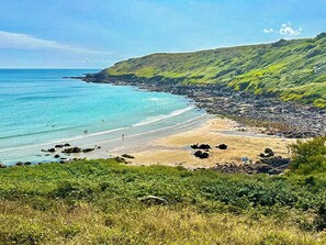 A coastal landscape with a beach, rocky shoreline, and lush greenery. - 2 bedroom accommodation in Coverack (Coverack)