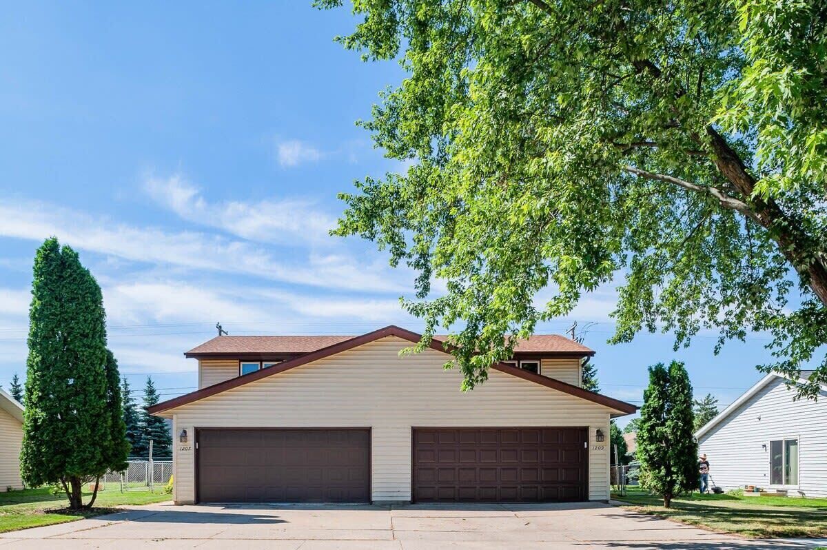 A two-story house with a garage and a well-maintained lawn.