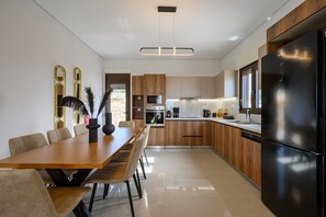 A modern kitchen with wooden cabinets, a black refrigerator, and a dining area with a wooden table and chairs.