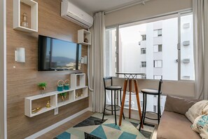 Uma sala de estar moderna com televisão de tela plana, estantes brancas, mesa de centro e um sofá.