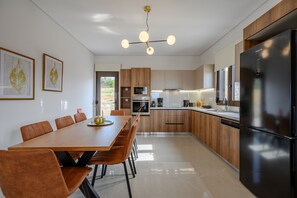 Une cuisine moderne avec des meubles en bois, un grand réfrigérateur noir et un coin repas comprenant une table et des chaises en bois.