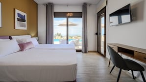 A hotel room with two beds, a desk, a TV, and a balcony with an umbrella.