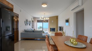 A modern kitchen with a built-in refrigerator, a dining area with a wooden table and chairs, and a living space with a sofa and TV.