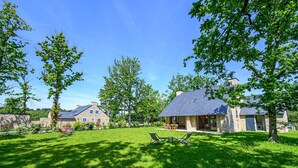 A stone house with a sloped roof, a patio with chairs, and a lawn. - Les Dryades - Villa familiale proche plage (Sarzeau)