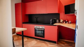 Eine kleine Küche mit roten Schränken, einer schwarzen Arbeitsplatte und einem eingebauten Backofen.