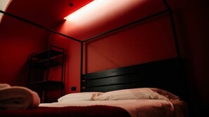 Ein Einzelbett mit Holz Kopfteil in einem Raum mit roten Wänden und einer schrägen Decke.
