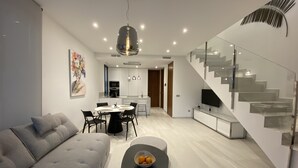 Een moderne woonkamer met een bank, een eettafel en een trap.