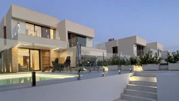 Een modern huis met een zwembad, terras en een trap naar de verdiepingen.