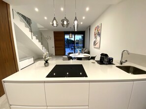 A modern kitchen with a central island, stainless steel appliances, and a dining area with a round table and chairs.