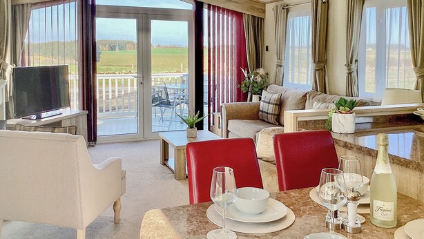 Een hotelkamer met een zithoek, een televisie en een balkon met uitzicht op het landschap.