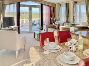 Une chambre d’hôtel dotée d’un coin repas, d’une télévision et d’un balcon offrant une vue sur la campagne.