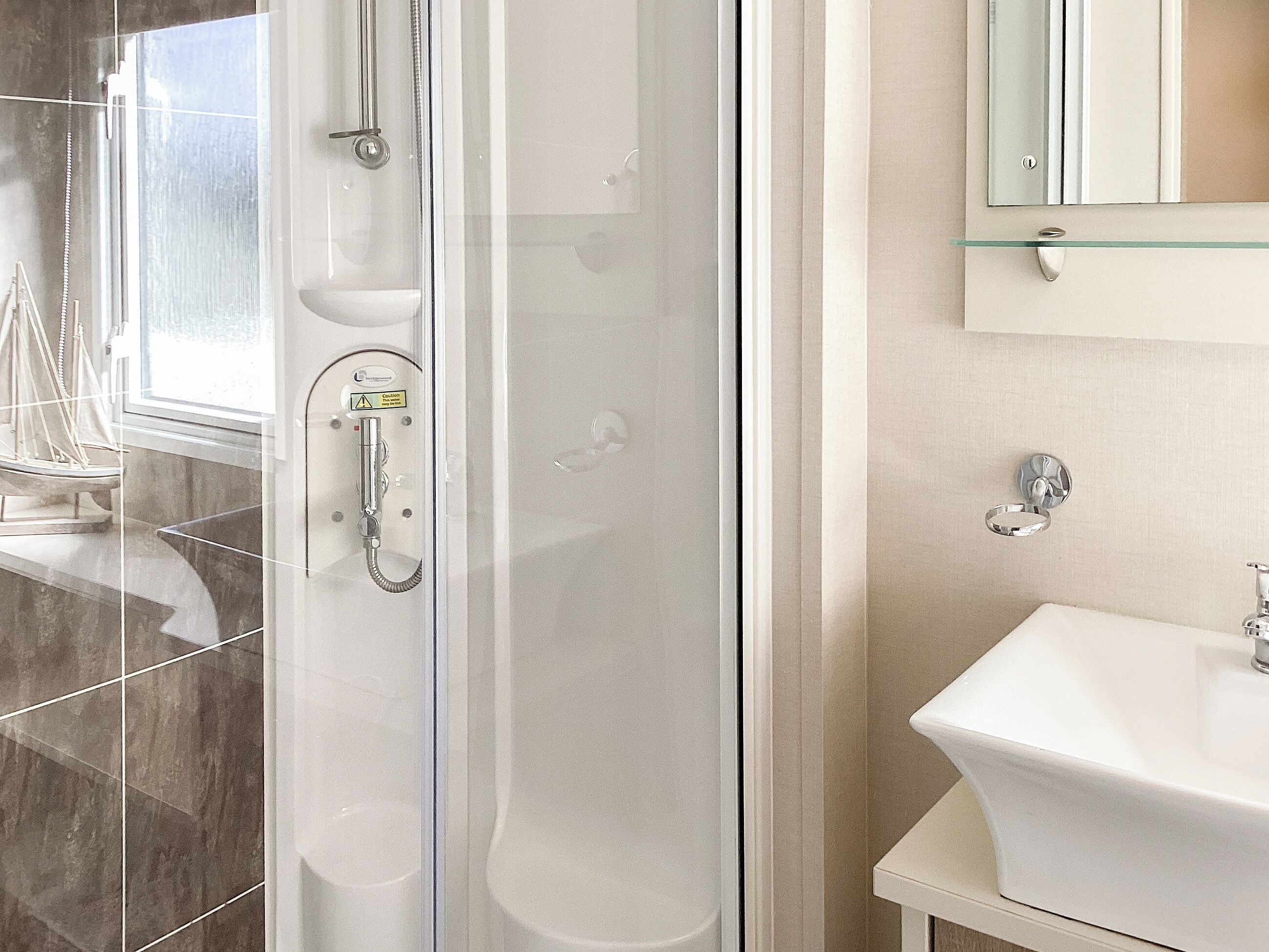 Une salle de bain avec une douche à parois de verre, un lavabo et un miroir.