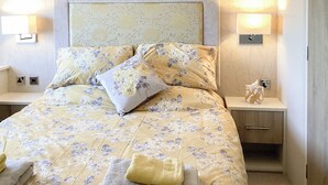 Een hotelkamer met een bed, twee nachtkastjes, een lamp en een zakdoekendoos.