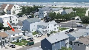 Ein Wohngebiet mit einer Mischung aus Reihen- und Mehrfamilienhäusern, einer gut sichtbaren Straße und einem Strand im Hintergrund.