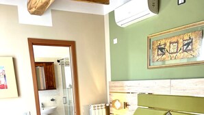 A neatly made bed with towels, a wooden headboard, a radiator, and a framed artwork on the wall. - Family room (Toscana)