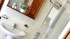 A bathroom with a sink, mirror, cabinet, and shower. - Family room (Toscana)