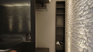 Ein modernes Schlafzimmer mit einer Steinwand, einem Bett, einem Sessel und einer eingebauten Regaleinheit.