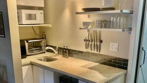 A modern kitchen with white cabinets, a built-in microwave, a toaster, and a dishwasher. - Creekside Mountain View Studio!Patio + BBQ,Pool,Parking & Walk to Shops and Lakes! (Whistler)
