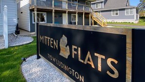 Opaste, jossa lukee ”Mitten Flats”, ja taustalla näkyy kaksikerroksinen rakennus.