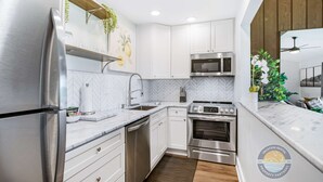 A modern kitchen with white cabinets, stainless steel appliances, and a herringbone tile backsplash. - Modern Lake Geneva Condo with Pool and Patio (Lake Geneva)