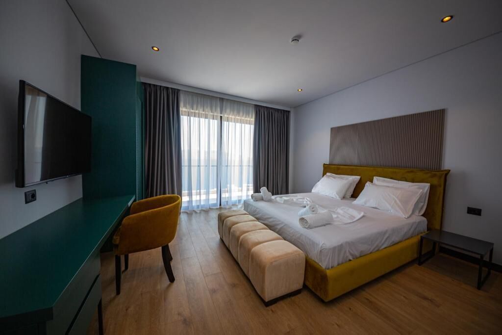 Une chambre d’hôtel moderne équipée d’un lit, d’un bureau, d’une chaise et d’un téléviseur.