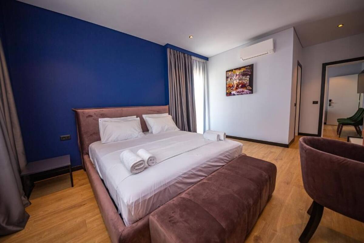 A modern hotel room with a large bed, a bench, and a chair.