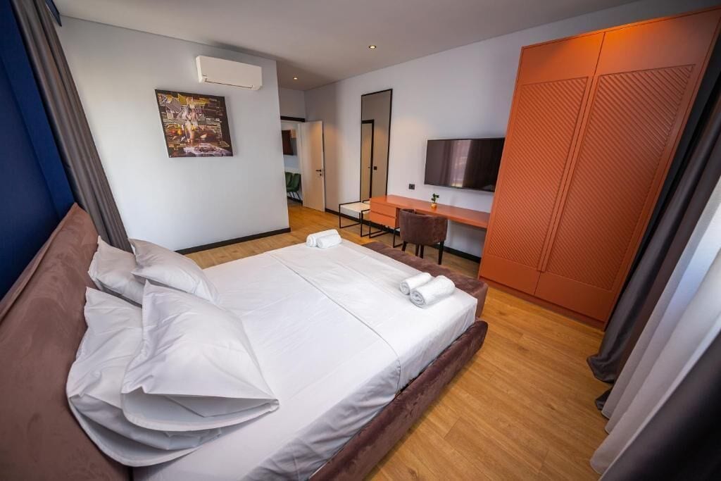 A hotel room with a bed, a desk, a TV, and a wardrobe.