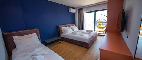 A hotel room with two beds, a TV, and a balcony with a hanging chair.