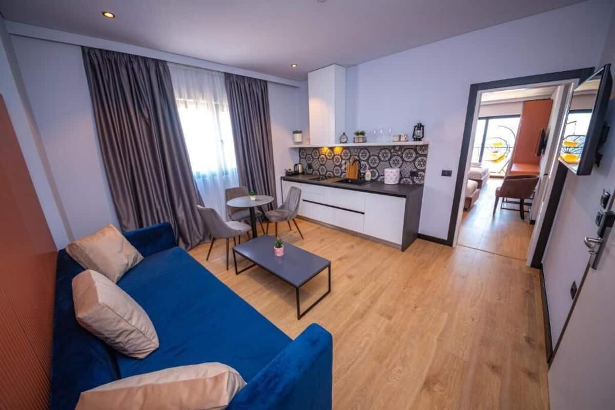 A modern living room with a blue sofa, a coffee table, and a dining area with chairs.
