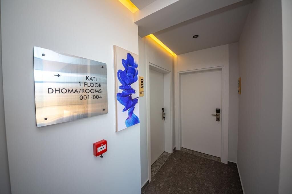 En gang med et skilt, der angiver "KATI 1 FLOOR DHOMA/ROOMS 001-004".