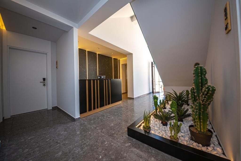 A modern interior with a reception desk, a plant area, and a door.