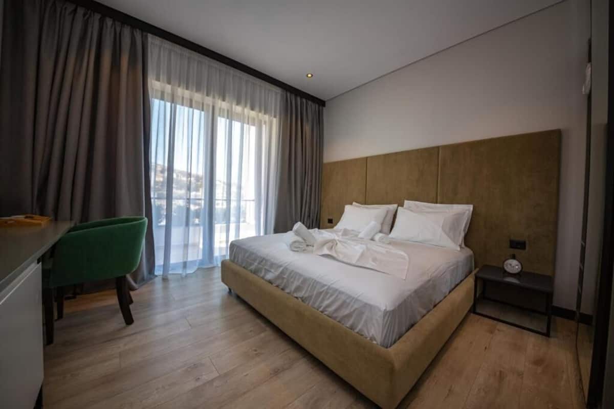 A modern hotel room with a large bed, a desk, and a chair.
