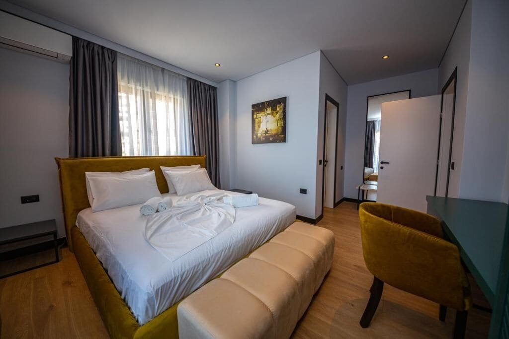 A hotel room with a bed, a bench, a desk, and a chair.