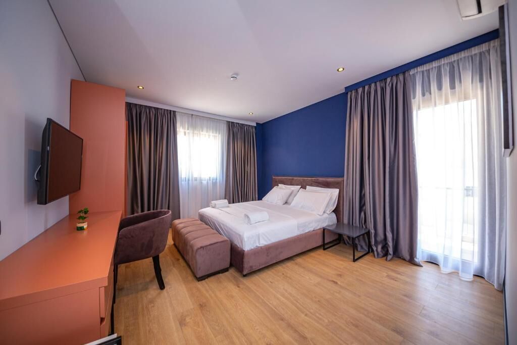 Ein modernes Hotelzimmer mit Bett, Schreibtisch und Fernseher.