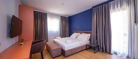 Ein modernes Hotelzimmer mit Bett, Schreibtisch und Fernseher.