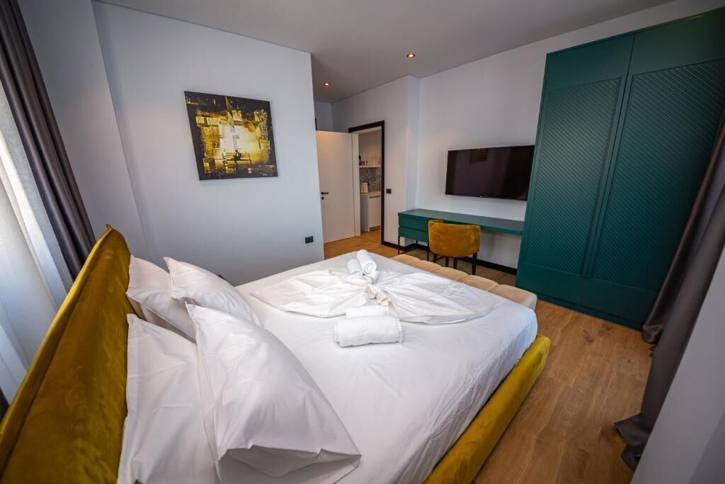 A hotel room with a bed, a desk, a chair, a television, and a wardrobe.