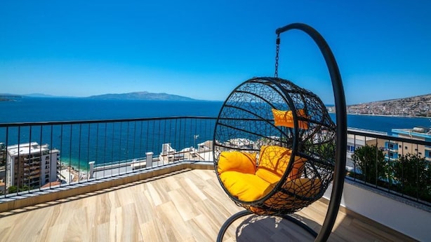 A balcony with a hanging chair overlooking a coastal view. - Apart-Hotel Lili2 (Sarandë)