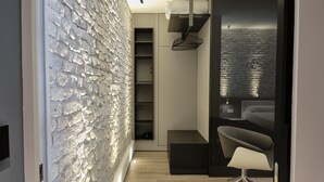 Un interior moderno con pared texturizada, un banco empotrado, una silla y una cama con cabecera.