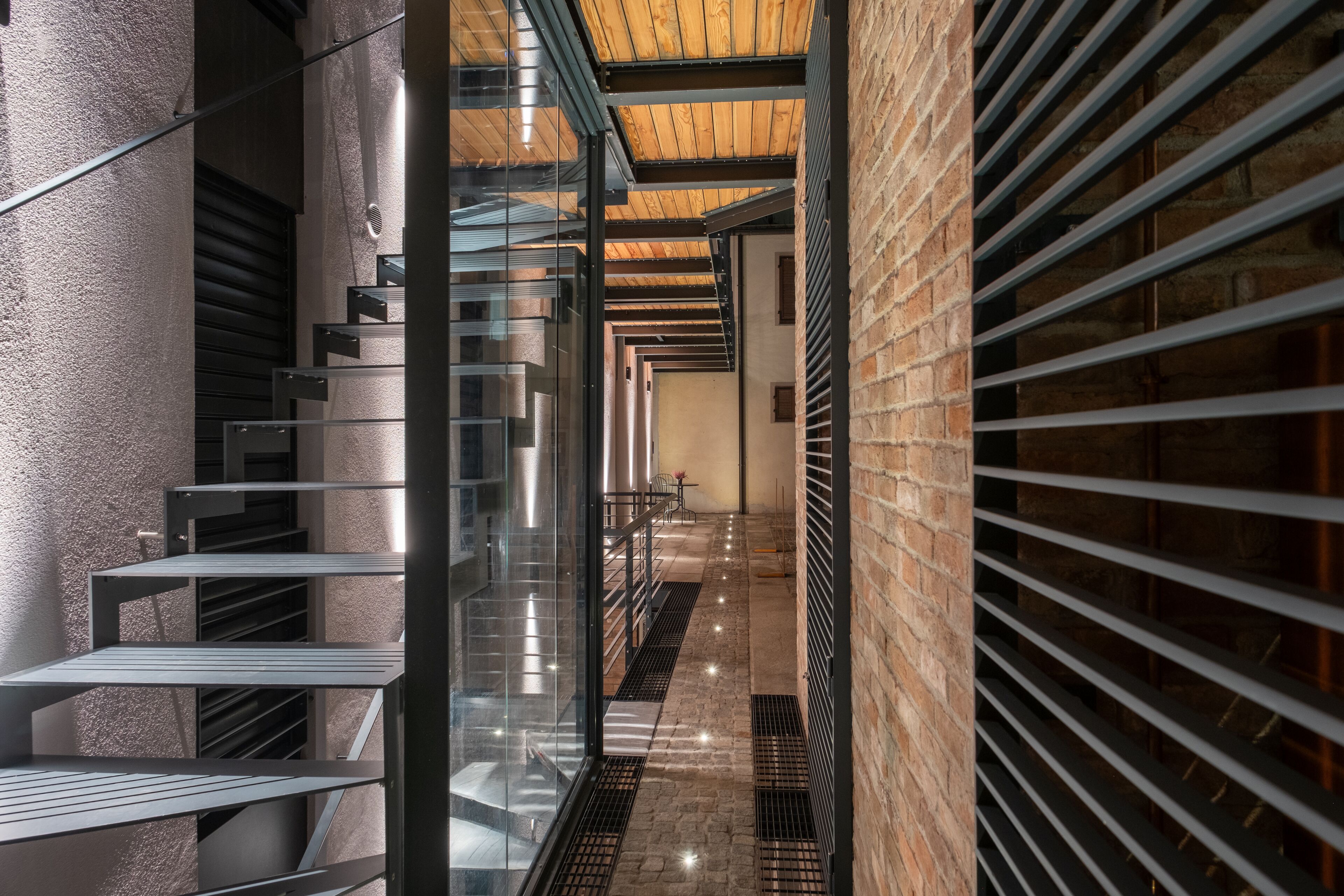 A modern interior with a staircase, metal railings, and brick walls.
